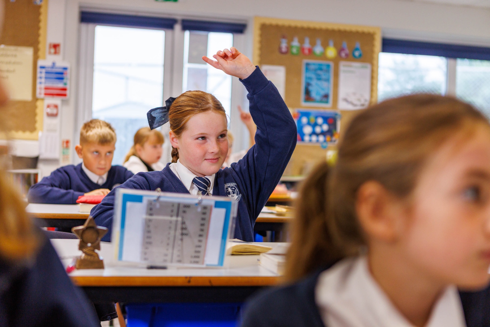 Child with her hand up in class at Mevagissey Community Primary School